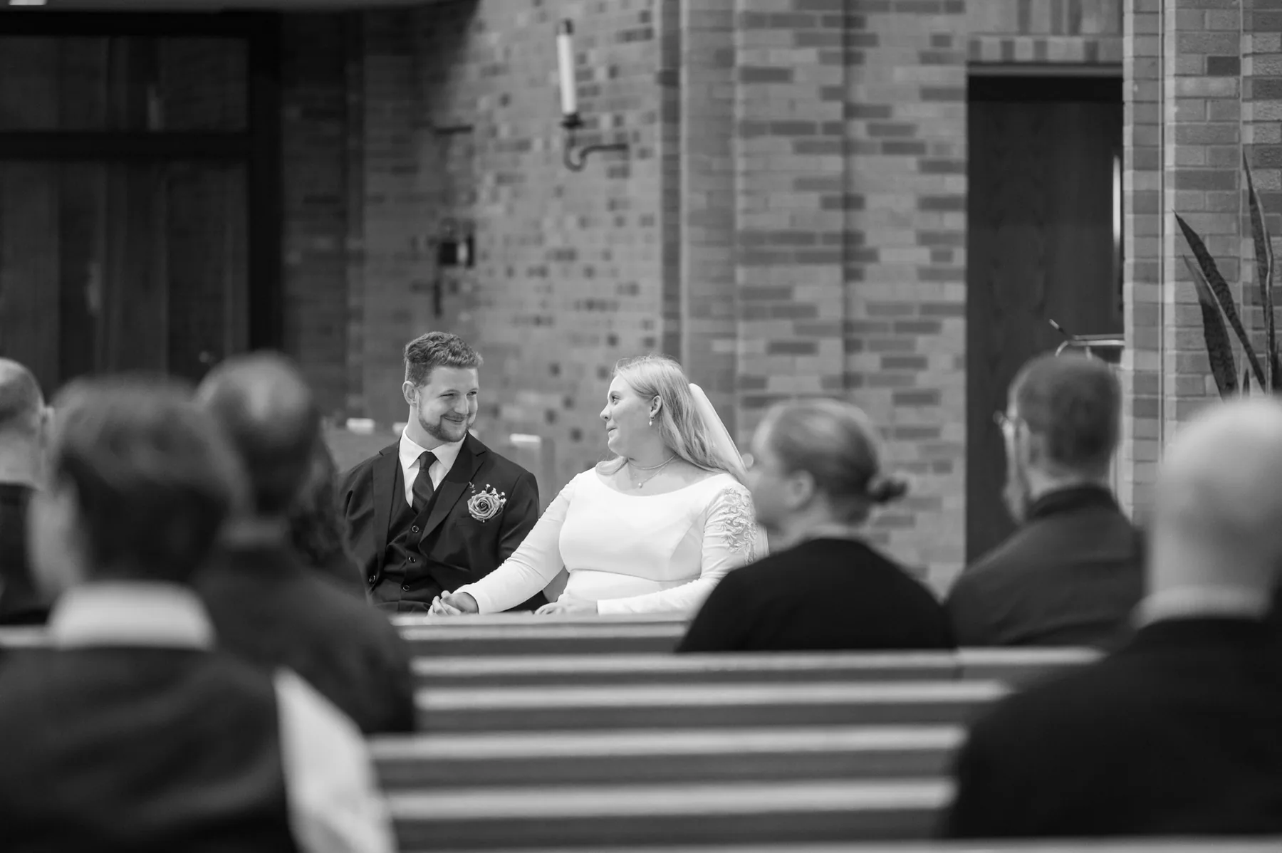 Kamryn and Isaiah seated together at the front of the church, turned slightly toward each other, both smiling