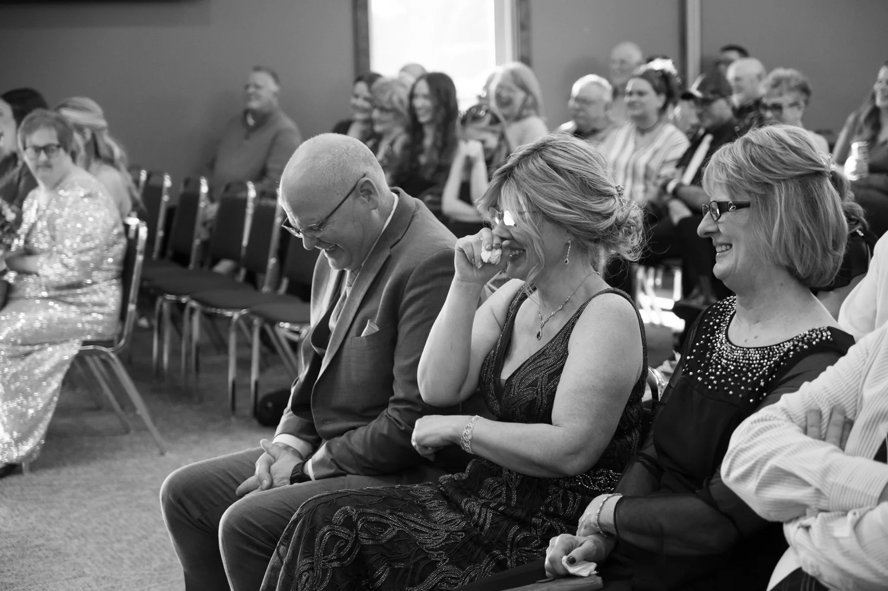 Devon's father with his head bowed during the ceremony, his mother pressing a tissue to her face beside him