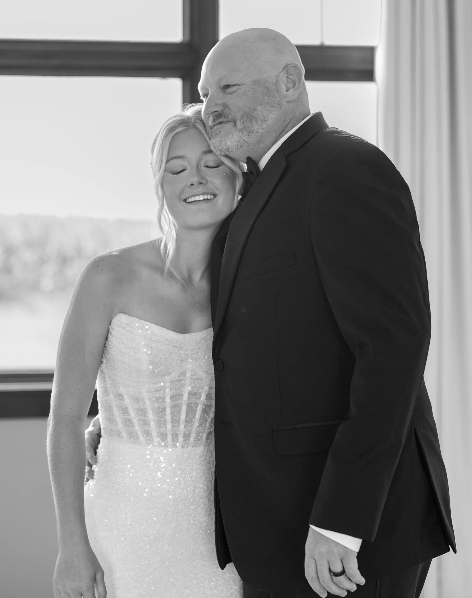 Rylee resting her head against her father's shoulder in window light, both of them smiling