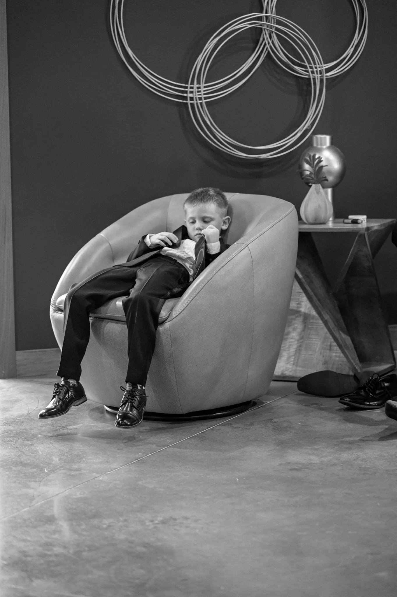 Young groomsman resting in a leather chair between wedding day moments
