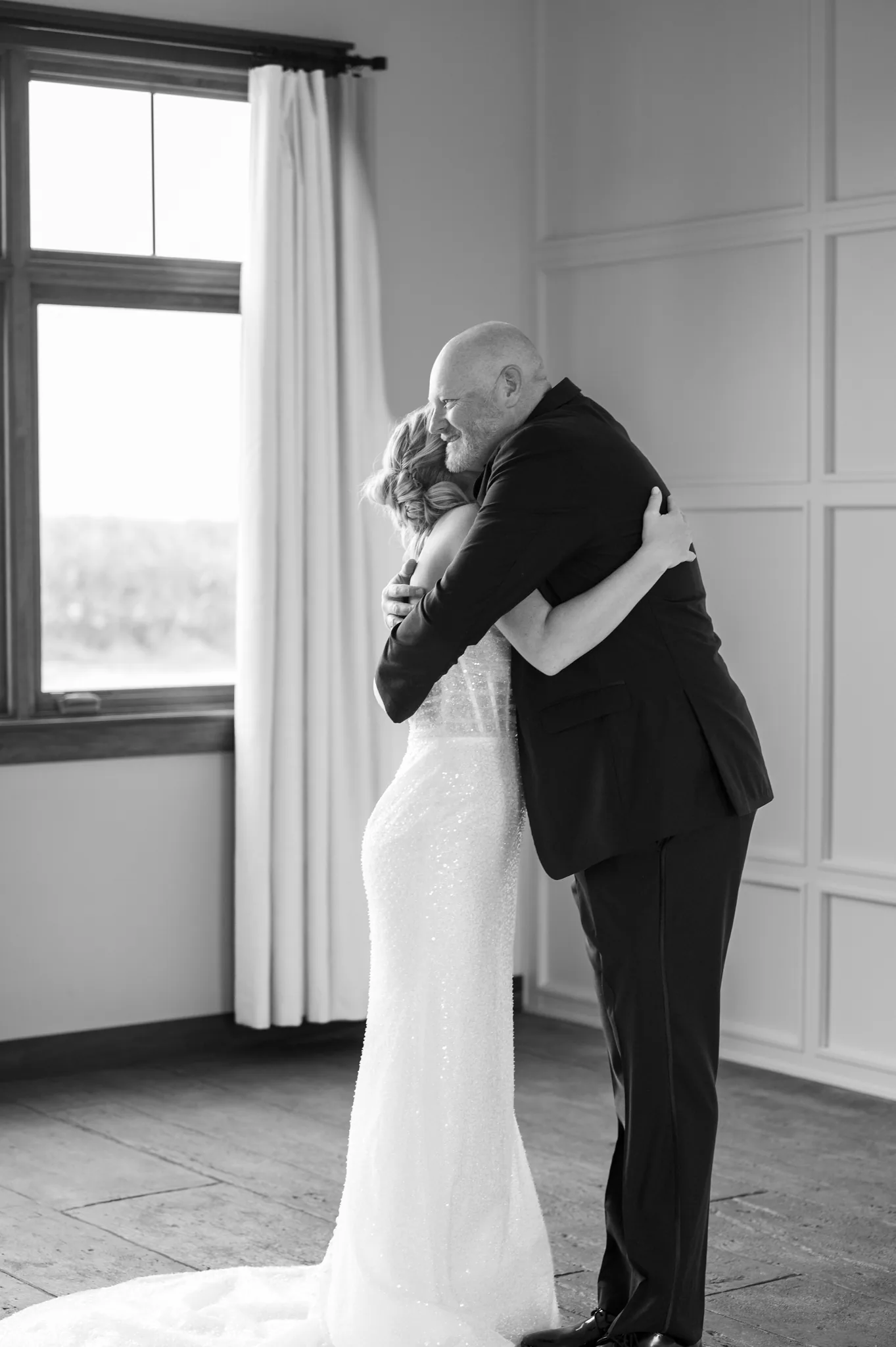 Rylee and her father holding each other in window light before the ceremony